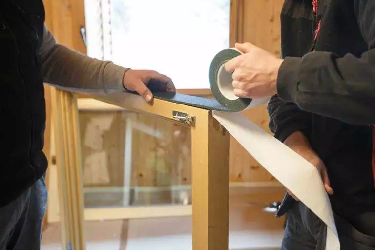 Close-up of timber window frame being prepared with insulation tape during installation — Cristal Windows, Doors & Conservatories
