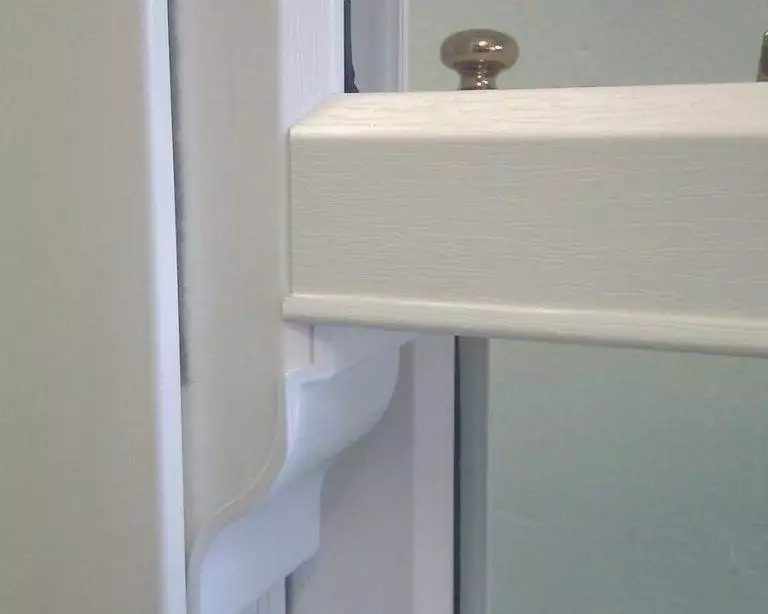 Close-up of white woodgrain-effect uPVC sliding sash window with decorative horn detail – Cristal Windows, Doors & Conservatories