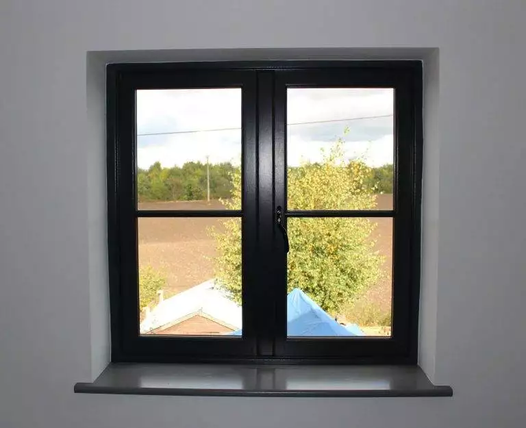 Black timber casement window with a rural view, closed position, white interior wall — Cristal Windows, Doors & Conservatories