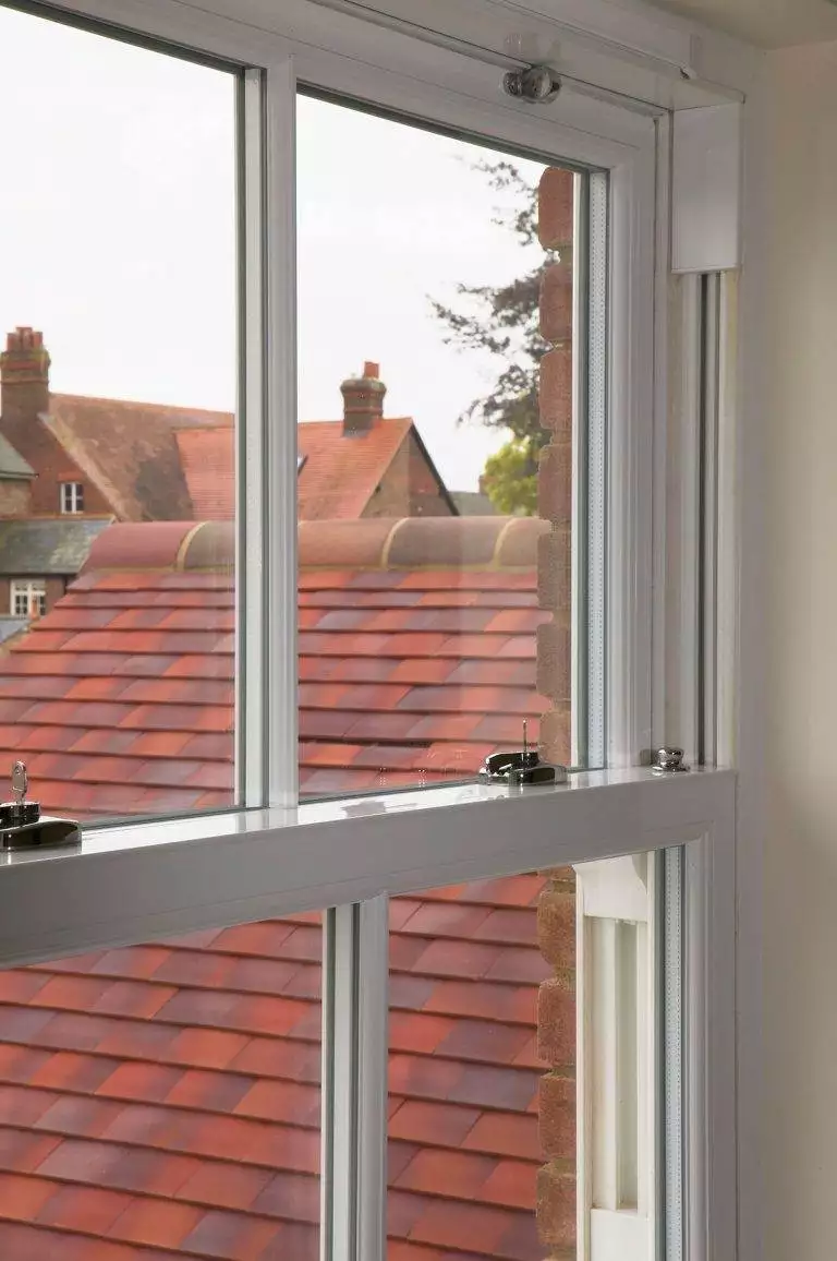 Interior view of white uPVC sliding sash window partially open, overlooking red tiled rooftops – Cristal Windows, Doors & Conservatories