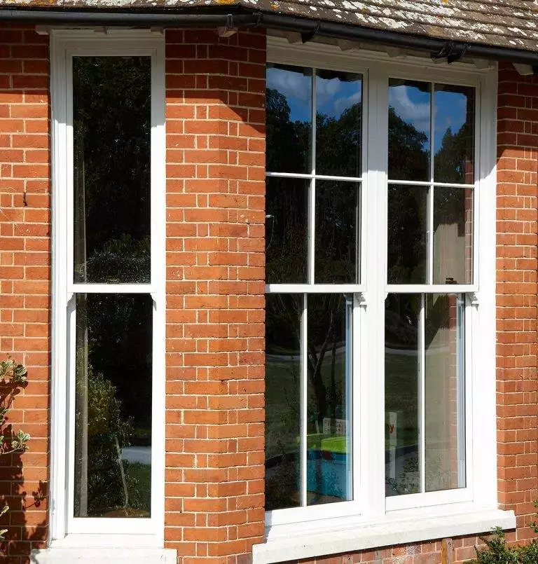 White uPVC sliding sash windows with astragal bars on a traditional red brick home – Cristal Windows, Doors & Conservatories