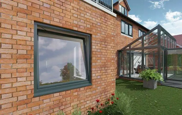 Modern brick home with dark-framed uPVC tilt and turn window partially open next to a glass conservatory – Cristal Windows, Doors & Conservatories