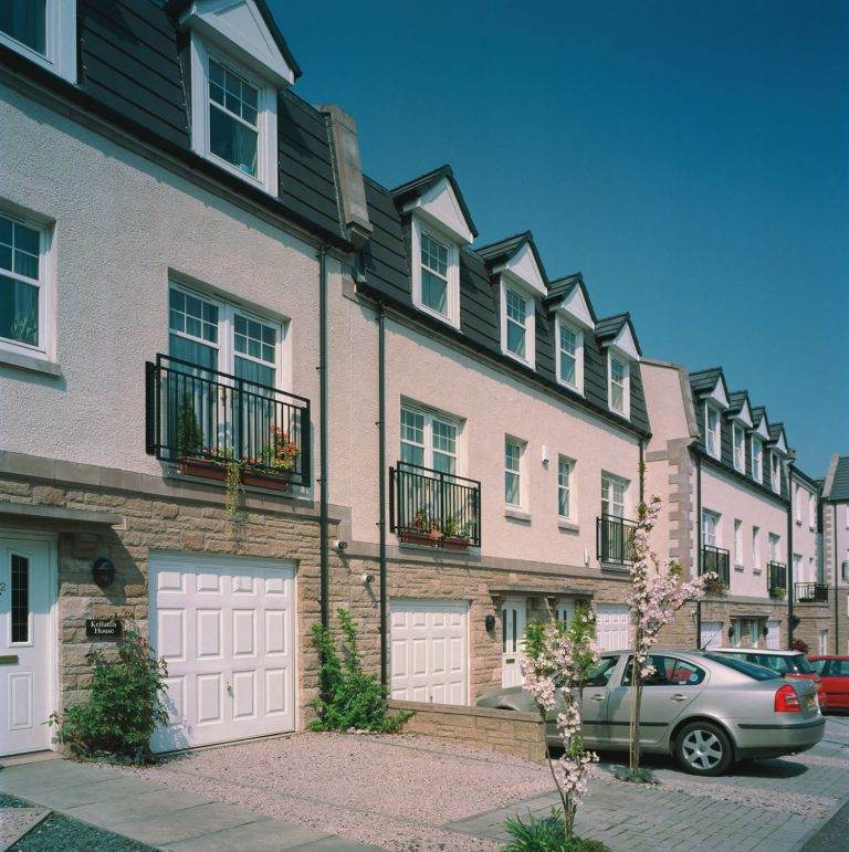 Row of modern townhouses with white panelled garage doors and balcony windows – Cristal Windows, Doors & Conservatories