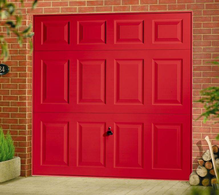 Bold red up-and-over garage door with raised rectangular panel design on a brick home exterior – Cristal Windows, Doors & Conservatories