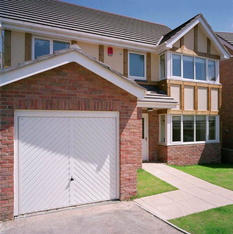 White up-and-over garage door with diagonal panel design on a brick-built home exterior – Cristal Windows, Doors & Conservatories