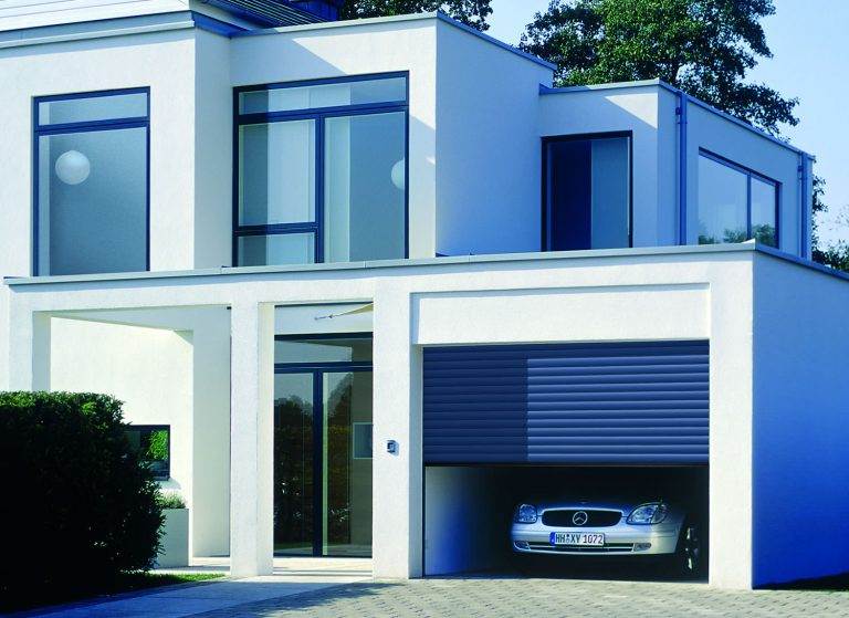 Contemporary home with a dark grey roller garage door partially open, revealing a Mercedes car – Cristal Windows, Doors & Conservatories