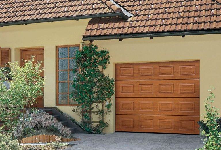 Light oak effect sectional garage door with rectangular panel design, complementing a cream exterior and tiled roof – Cristal Windows, Doors & Conservatories