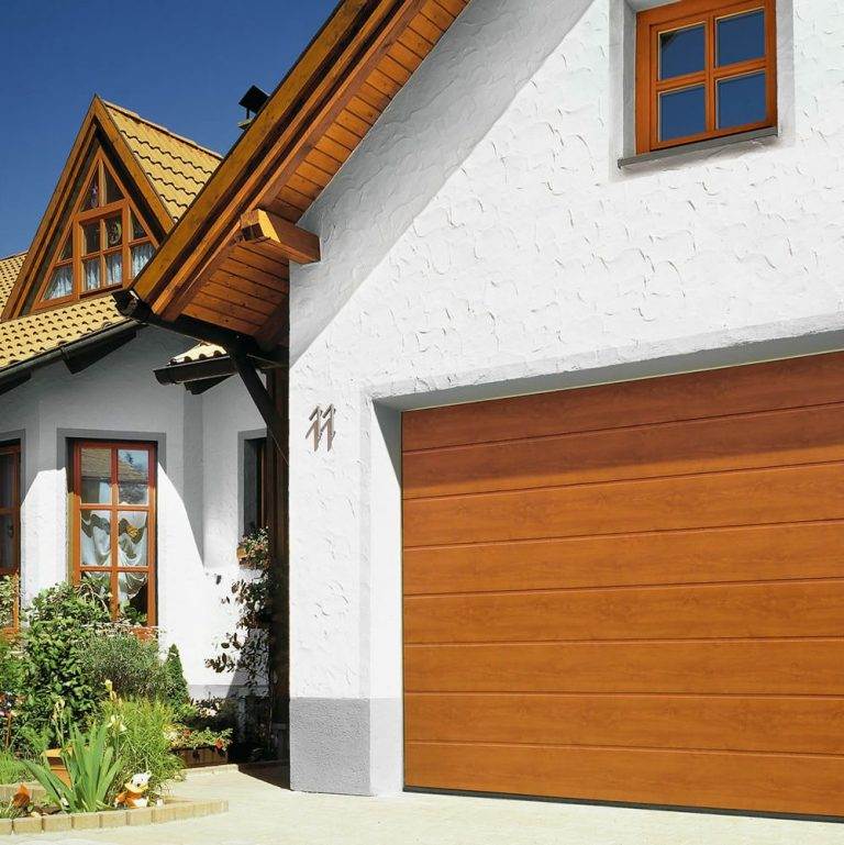 Golden oak horizontal panel sectional garage door complementing a white rendered house with matching wooden window frames – Cristal Windows, Doors & Conservatories