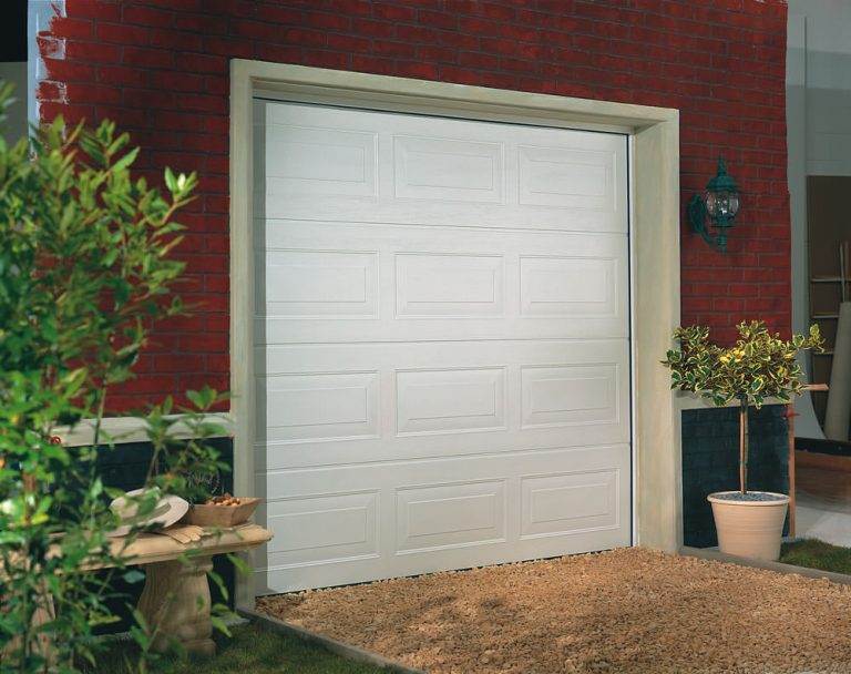 White sectional garage door with rectangular panel design fitted to a red brick house exterior – Cristal Windows, Doors & Conservatories
