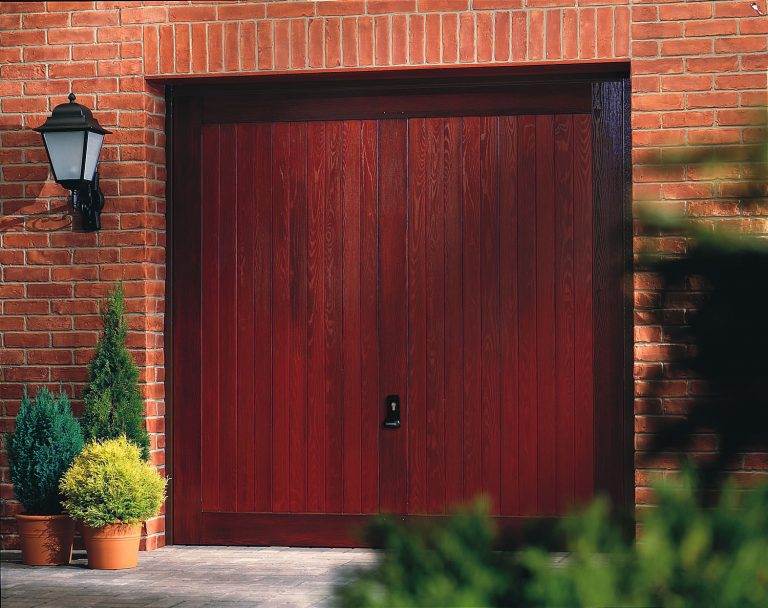 Traditional timber-effect up and over garage door in deep red finish, surrounded by brickwork – Cristal Windows, Doors & Conservatories