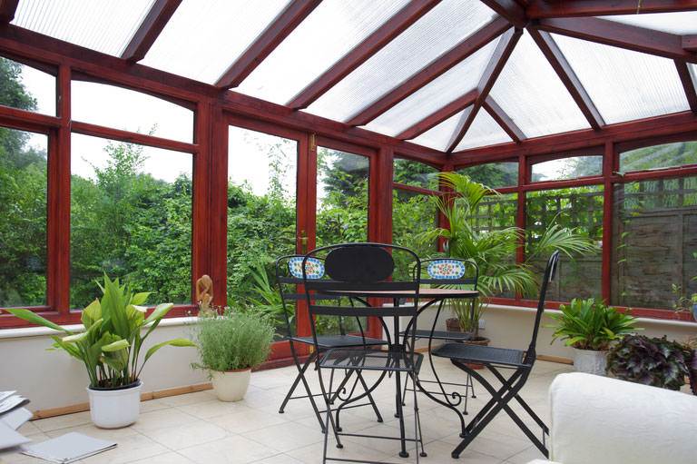 Edwardian conservatory with pitched glass roof and timber-effect frame, styled with indoor plants – Cristal Windows, Doors & Conservatories