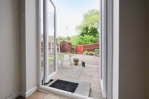 White uPVC French doors opening onto a garden patio with outdoor seating – Cristal Windows, Doors & Conservatories