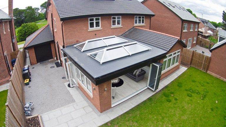 Flat roof extension with twin glass roof lanterns and bi-fold doors opening to garden – Cristal Windows, Doors & Conservatories