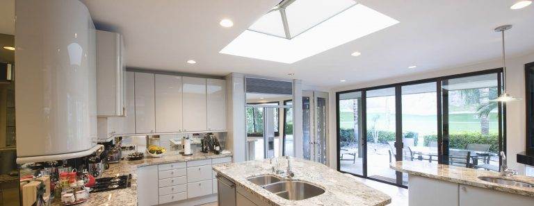 Contemporary kitchen with roof lantern skylight and sliding glass doors for a bright open-plan design – Cristal Windows, Doors & Conservatories