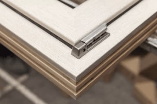 Close-up of timber window corner in light finish with visible hinge, shown during production with no exterior view — Cristal Windows, Doors & Conservatories