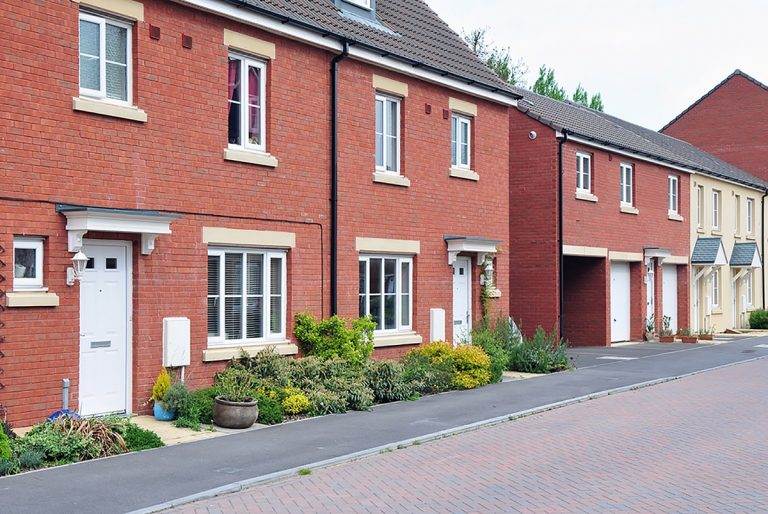 Row of modern red brick homes with white uPVC casement windows and landscaped front gardens - Cristal Windows, Doors & Conservatories