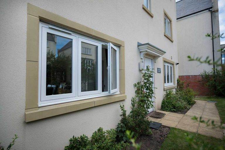 White uPVC flush casement window partially open on a modern cream-coloured home exterior with stone trim – Cristal Windows, Doors & Conservatories