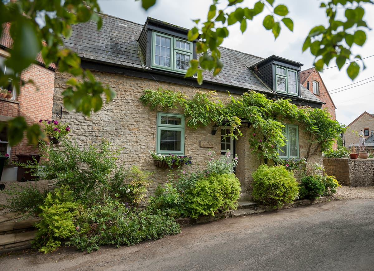 Charming stone cottage with green uPVC double glazed windows and lush greenery - Cristal Windows, Doors & Conservatories