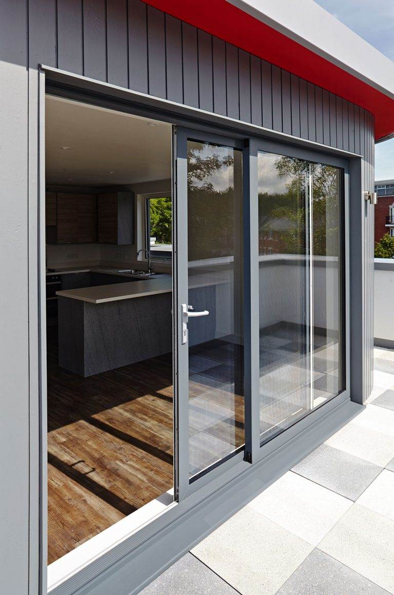 Grey aluminium patio doors leading from modern kitchen to balcony – Cristal Windows, Doors & Conservatories