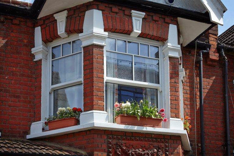 White uPVC sliding sash bay window with decorative glazing on a Victorian red brick house – Cristal Windows, Doors & Conservatories