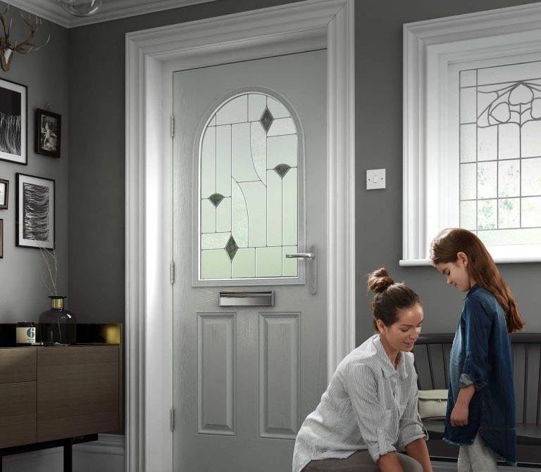 Interior view of light grey composite front door with decorative arched glazing and chrome handle – Cristal Windows, Doors & Conservatories