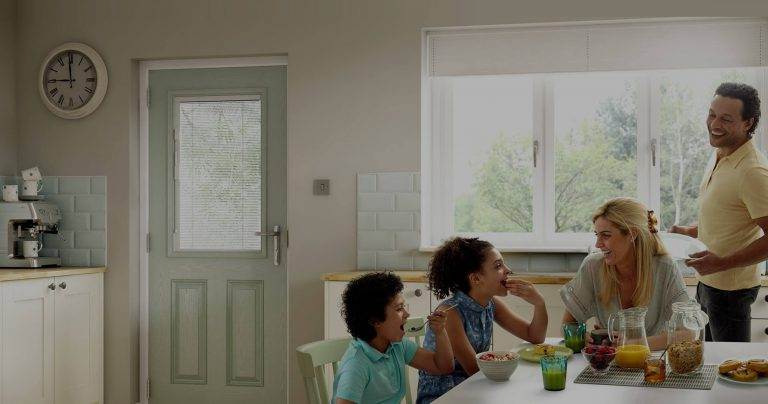 Family kitchen with light green composite door featuring glazed panel and chrome handle – Cristal Windows, Doors & Conservatories