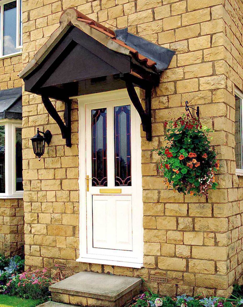 White uPVC front door with decorative glass panels and gold handle, fitted into a stone house exterior – Cristal Windows, Doors & Conservatories