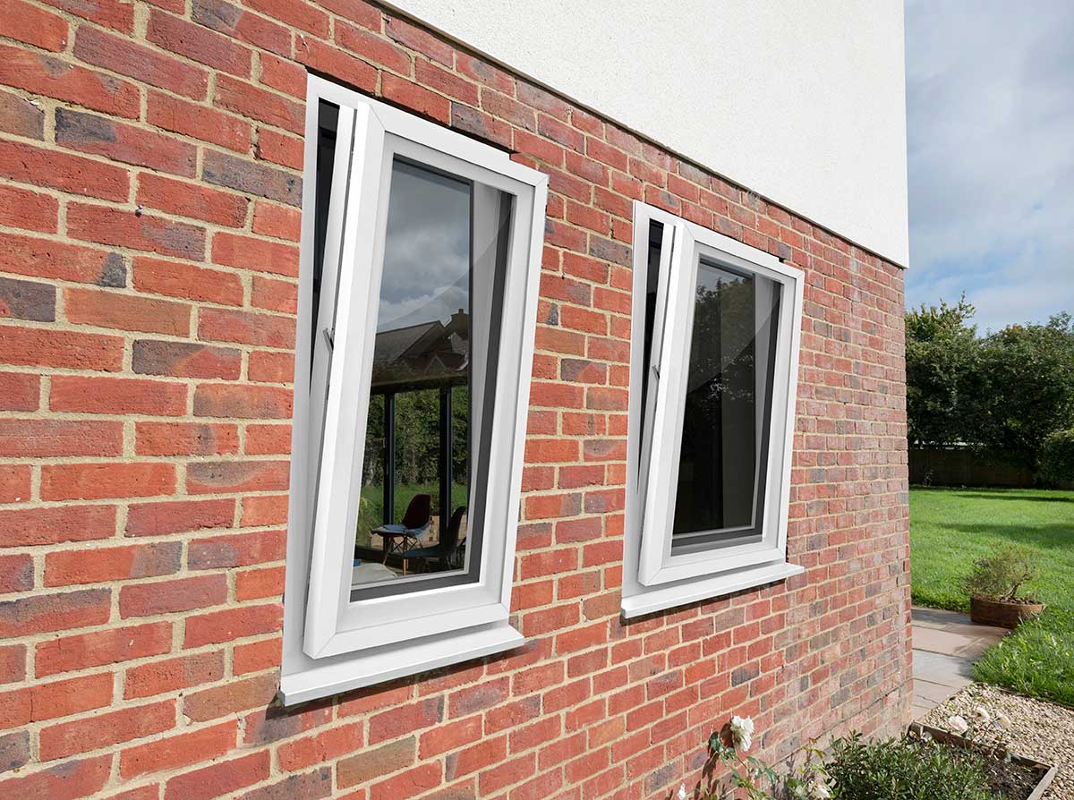 White uPVC tilt and turn windows partially open on a red brick exterior wall of a modern home – Cristal Windows, Doors & Conservatories