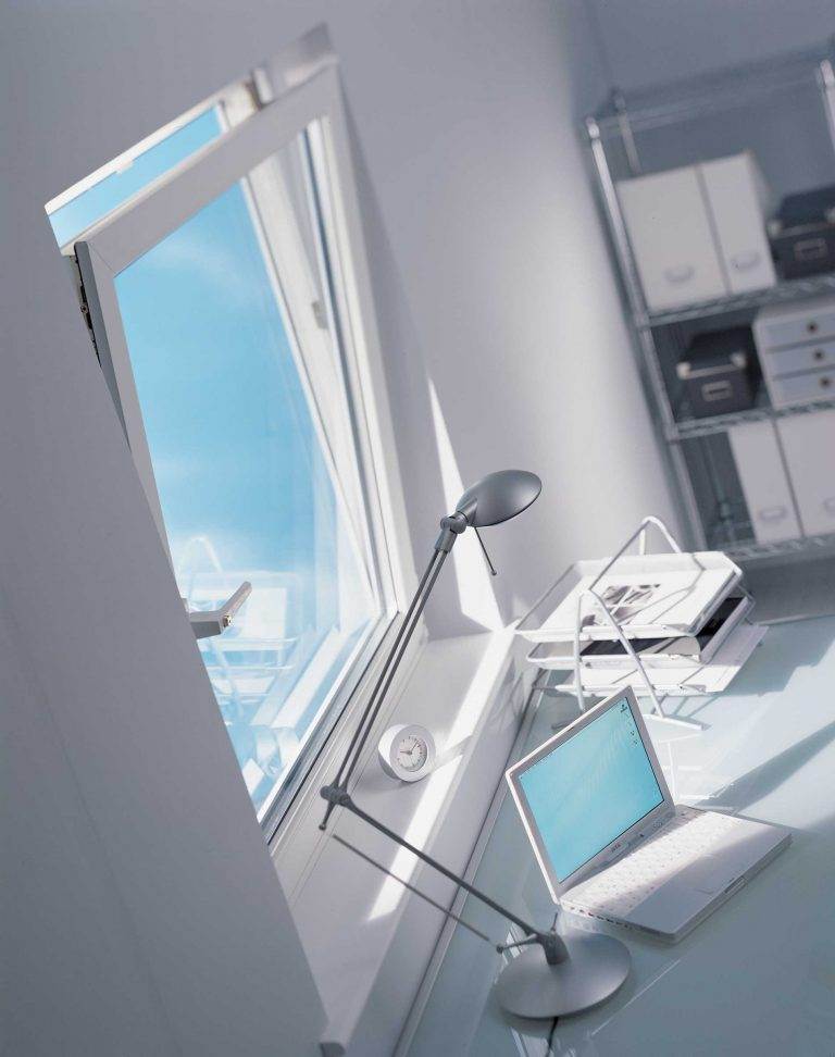 White uPVC tilt and turn window in a modern home office, shown tilted open beside a desk with a laptop – Cristal Windows, Doors & Conservatories