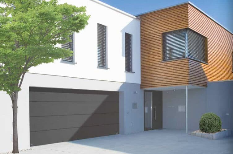 Contemporary home with a sleek black sectional garage door and modern timber cladding – Cristal Windows, Doors & Conservatories
