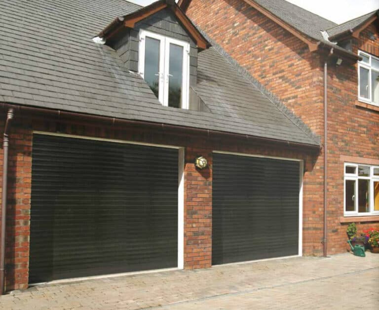 Traditional brick home featuring dual black roller garage doors for secure and stylish vehicle storage – Cristal Windows, Doors & Conservatories