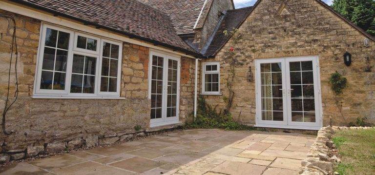 White uPVC French doors with Georgian bars opening onto a stone patio of a traditional cottage – Cristal Windows, Doors & Conservatories