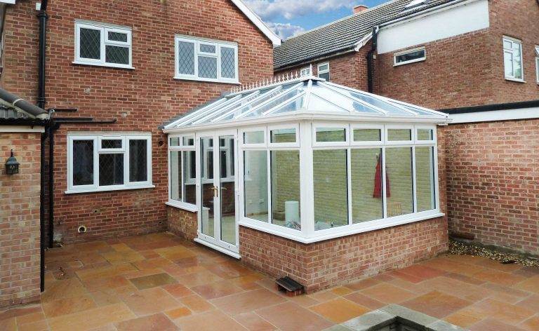 Edwardian style conservatory with pitched glass roof and white uPVC frame on brick extension – Cristal Windows, Doors & Conservatories