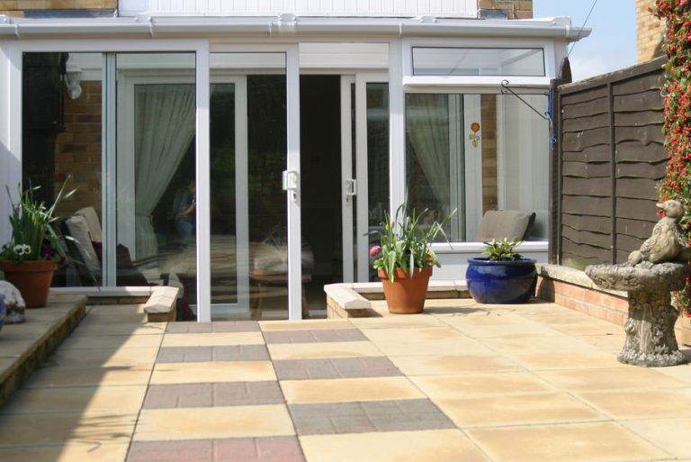 Lean-to conservatory with white uPVC frame and sliding glass doors opening to patio – Cristal Windows, Doors & Conservatories