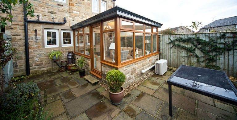 Georgian conservatory with timber-effect frame and glass roof on stone extension – Cristal Windows, Doors & Conservatories