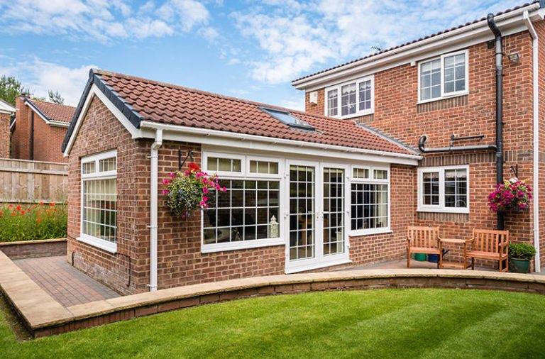 Traditional orangery with tiled pitched roof, large grid windows and French doors on brick extension – Cristal Windows, Doors & Conservatories