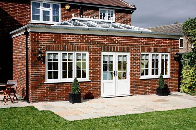 Modern orangery extension with glass lantern roof and red brick walls featuring French doors – Cristal Windows, Doors & Conservatories