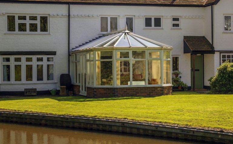 Victorian conservatory with pitched glass roof and white uPVC frame on brick base – Cristal Windows, Doors & Conservatories