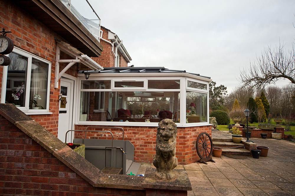 Victorian conservatory with white uPVC frame and glass roof on red brick extension – Cristal Windows, Doors & Conservatories