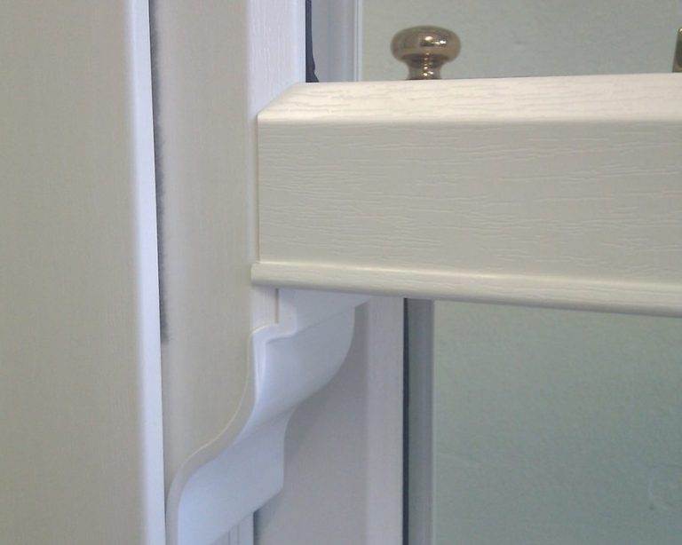Close-up of white woodgrain-effect uPVC sliding sash window with decorative horn detail – Cristal Windows, Doors & Conservatories