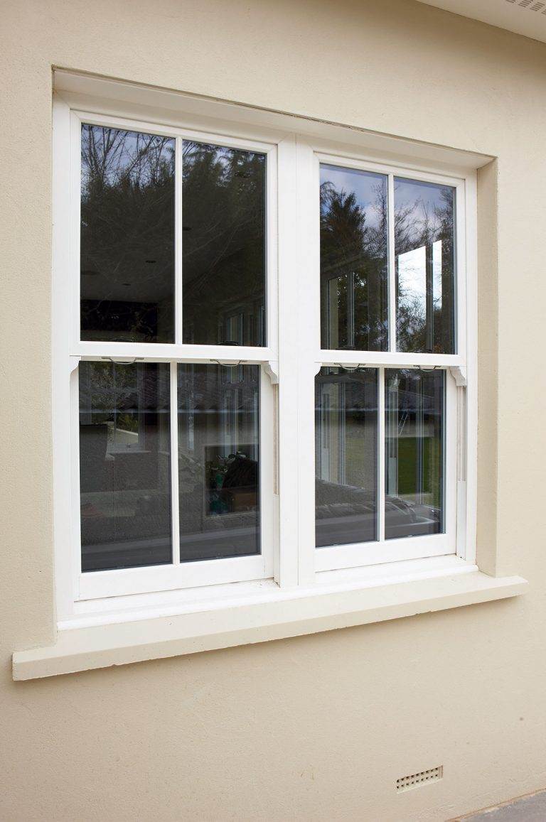 White uPVC sliding sash window with slimline astragal bars on a cream rendered exterior – Cristal Windows, Doors & Conservatories