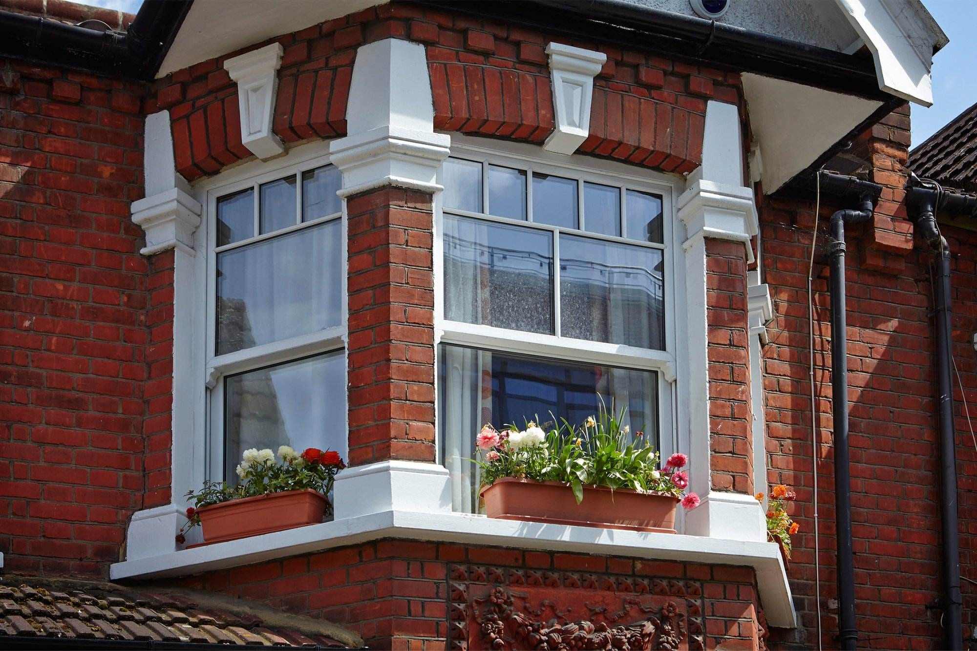 White uPVC sliding sash bay window with decorative glazing on a Victorian red brick house – Cristal Windows, Doors & Conservatories