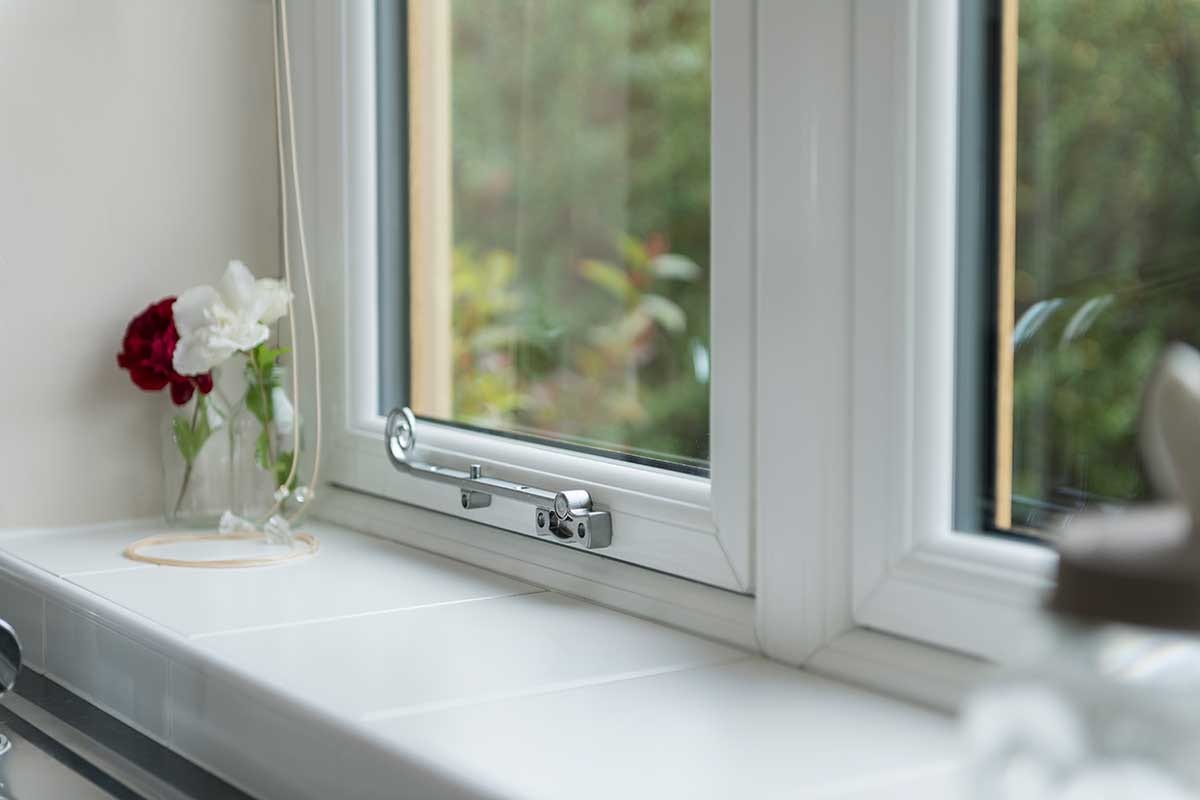 Interior view of white uPVC double glazed window with chrome handle and tiled windowsill - Cristal Windows, Doors & Conservatories