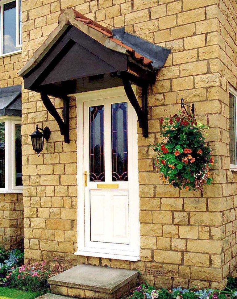 White uPVC front door with decorative glass panels and gold handle, fitted into a stone house exterior – Cristal Windows, Doors & Conservatories