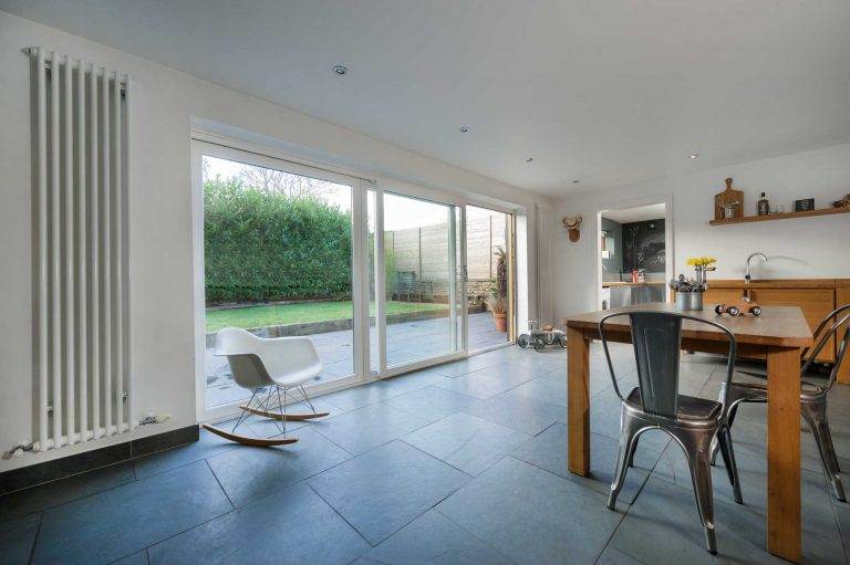 Modern kitchen and dining area with large white uPVC patio sliding doors opening to a garden – Cristal Windows, Doors & Conservatories