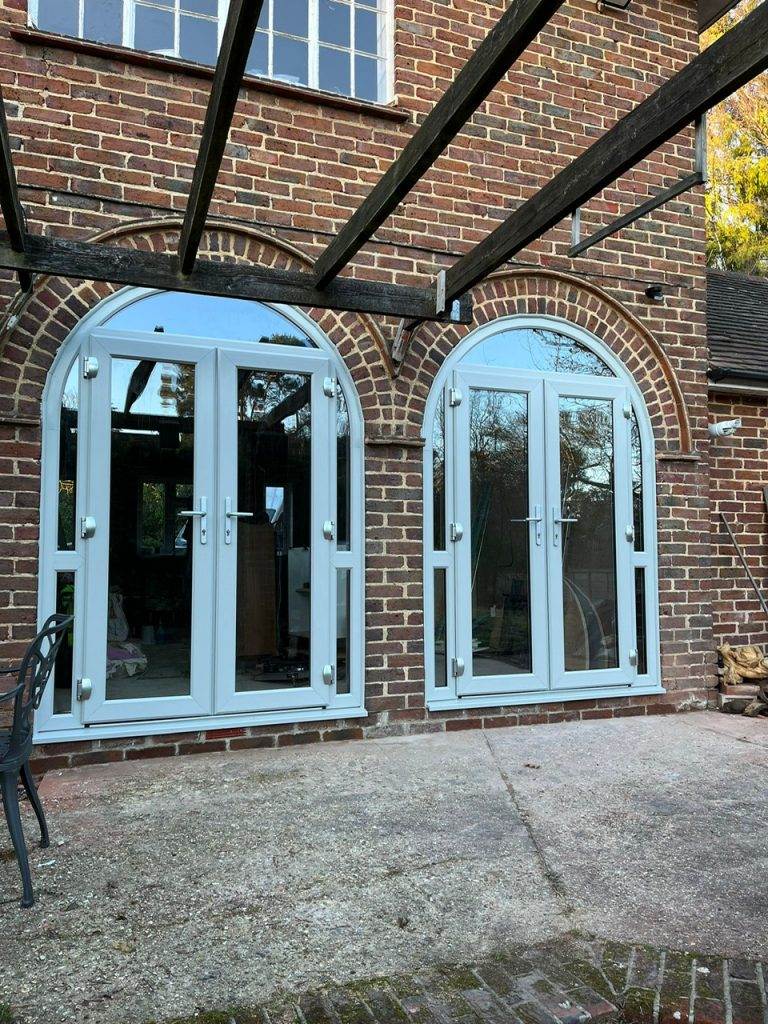 White arched bespoke French doors with matching side panels set in red brick wall – Cristal Windows, Doors & Conservatories