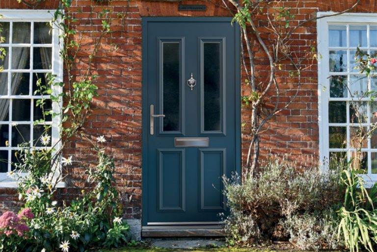 Dark blue aluminium composite front door with decorative glazing panels and chrome hardware set in red brick wall – Cristal Windows, Doors & Conservatories