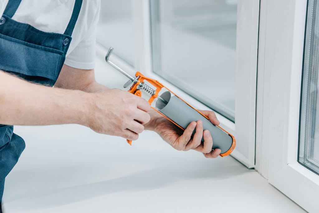 Close-up of Installer Applying Silicone Sealant Around Double Glazed Window Frame