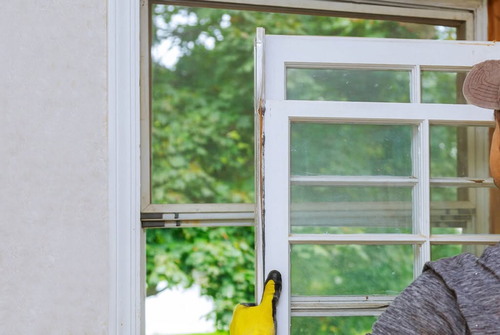 Installer Carefully Removing Old Window Frame from Opening
